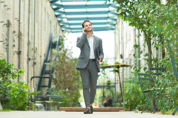 A young successful businessman is working outdoor using smartphone. Man in a casual wear. Business, freelance and remote work.