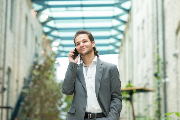 Un joven empresario exitoso está trabajando al aire libre con un teléfono inteligente. Un hombre con ropa casual. Negocios, freelance y trabajo remoto. — Foto de Stock