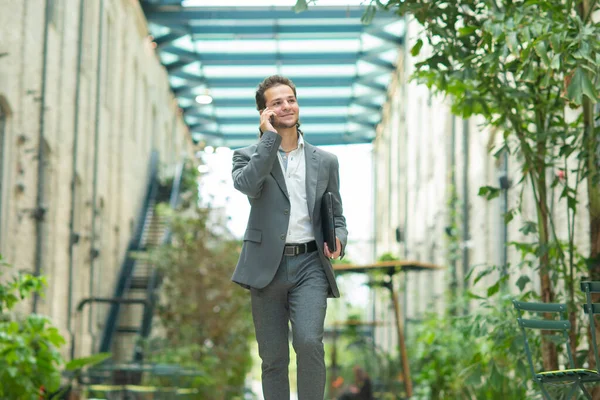 A young successful businessman is working outdoor using smartphone. Man in a casual wear. Business, freelance and remote work. — Stock Photo, Image