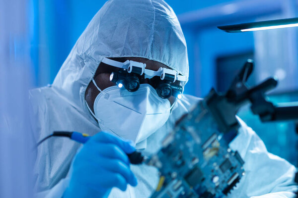 Афроамериканский ученый работает в современной научной лаборатории по исследованию и разработке микроэлектроники и процессоров. Производственный работник использует компьютерные технологии и оборудование.