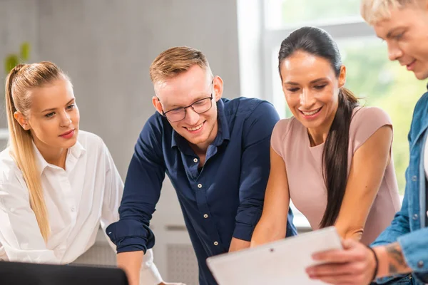 Team of young and confident startupers is working at the table in the office, discussing the strategy and development plan of the company. Business, innovation, brainstorming and teamwork. — Stock Photo, Image