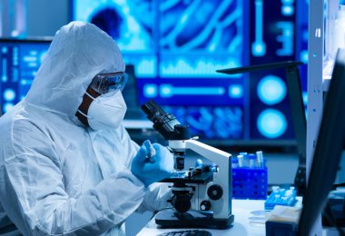 Koruyucu kıyafetli Afrikalı-Amerikalı doktor modern bir laboratuvarda bilimsel deneyler yapıyor ve aşı geliştiriyor. Laboratuvar asistanı iş yerinde. Bilim ve tıp kavramı.