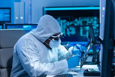 Afrikalı-Amerikalı bilim adamı, mikro elektronik ve işlemcilerin araştırılması ve geliştirilmesi için modern bir bilim laboratuvarında çalışıyor. Üretim işçisi bilgisayar teknolojisi ve ekipmanı kullanıyor.