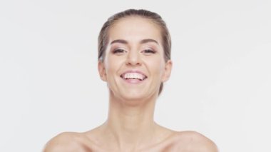 Genç, çekici ve sağlıklı bir kadının güzel portresi. Esmer kız beyaz arka planda gülüyor. Doğal kadın yüzü..