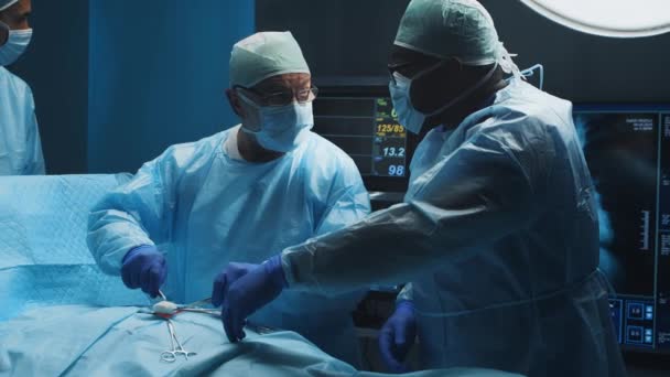 Tim ahli bedah medis profesional multirasial melakukan operasi bedah di sebuah rumah sakit modern. Dokter sedang bekerja untuk menyelamatkan pasien. Kedokteran, kesehatan, kardiologi dan transplantasi. — Stok Video