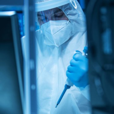 Bilim adamı modern bir laboratuarda laboratuvar ekipmanları, mikroskop ve bilgisayar teknolojisi kullanıyor. Yeni aşıların icadı. Bilim ve Sağlık kavramı.