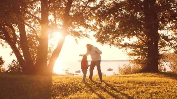 Liefdevolle familie wandelingen op het platteland tijdens zonsondergang. Vader speelt met zijn zoon. Het concept van liefde, ouderlijke zorg en kinderen. — Stockvideo