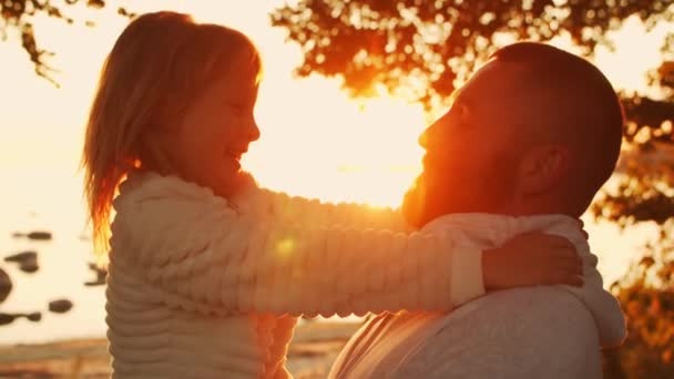 Liebevolle Familienspaziergänge in der Natur während des Sonnenuntergangs. Vater spielt mit seiner Tochter. Das Konzept der Liebe, der elterlichen Sorge und der Kinder. — Stockvideo