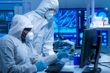 Afrikalı-Amerikalı bilim adamı laboratuvar ekipmanları, mikroskop ve bilgisayar teknolojisi kullanarak bir laboratuarda çalışıyor. Yeni ilaçların ve aşıların icadı. Bilim ve Sağlık kavramı.