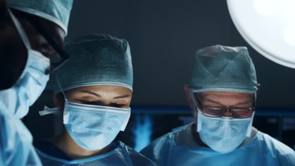 Multiraciale team van professionele chirurgen voert de chirurgische ingreep in een modern ziekenhuis. Artsen proberen de patiënt te redden. Geneeskunde, gezondheid, cardiologie en transplantatie. — Stockvideo