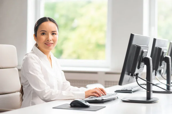 Donna d'affari asiatica sta lavorando al suo tavolo in un ufficio moderno. Il posto di lavoro di uno specialista di successo. Affari, fiducia e finanza. — Foto Stock