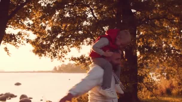 Люблячі сімейні прогулянки по селах під час заходу сонця. Батько грає зі своїм сином. Поняття любові, батьківського піклування та дітей . — стокове відео