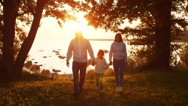 Amar los paseos familiares en el campo durante el atardecer. Mamá y papá abrazan y juegan con su hijo y su hija. El concepto de amor, cuidado parental e hijos. — Vídeos de Stock