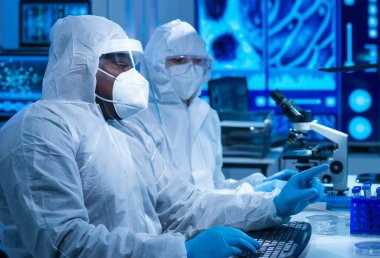 Afrikalı-Amerikalı bilim adamı laboratuvar ekipmanları, mikroskop ve bilgisayar teknolojisi kullanarak bir laboratuarda çalışıyor. Yeni ilaçların ve aşıların icadı. Bilim ve Sağlık kavramı.