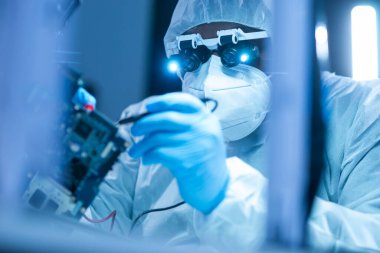 Afrikalı-Amerikalı bilim adamı, mikro elektronik ve işlemcilerin araştırılması ve geliştirilmesi için modern bir bilim laboratuvarında çalışıyor. Üretim işçisi bilgisayar teknolojisi ve ekipmanı kullanıyor.