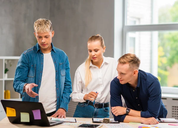 Team of young and confident startupers is working at the table in the office, discussing the strategy and development plan of the company. Business, innovation, brainstorming and teamwork. — Stock Photo, Image