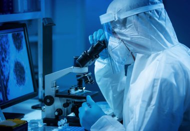 Bilim adamı modern bir laboratuarda laboratuvar ekipmanları, mikroskop ve bilgisayar teknolojisi kullanıyor. Yeni aşıların icadı. Bilim ve Sağlık kavramı.