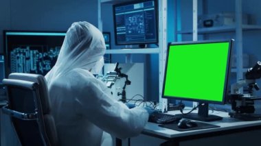 Bilim adamı, mikro elektronik ve işlemcilerin araştırma ve geliştirilmesi için modern bir bilim laboratuvarında çalışıyor. Mikroişlemci imalat işçisi krom anahtar yeşil ekranlı bilgisayar kullanıyor.