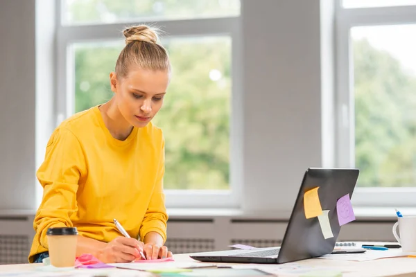 Local de trabalho do trabalhador independente ou de uma estudante no escritório em casa. Jovem mulher trabalha usando computador e outros dispositivos. Conceito de trabalho remoto. — Fotografia de Stock