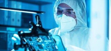 Bilim adamı mikro elektronik ve işlemcilerin araştırılması ve geliştirilmesi için modern bir bilim laboratuvarında çalışıyor. Mikroişlemci imalat işçisi bilgisayar teknolojisi ve ekipmanı kullanıyor.