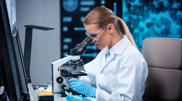 Vrouwelijke arts werkt in een modern wetenschappelijk laboratorium met behulp van apparatuur en computertechnologieën. De wetenschapper doet onderzoek en ontwikkelt nieuwe vaccins. Concept wetenschap en gezondheidszorg. — Stockfoto