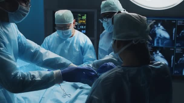 Multiracial team of professional medical surgeons performs the surgical operation in a modern hospital. Doctors are working to save the patient. Medicine, health, cardiology and transplantation. — Stock Video