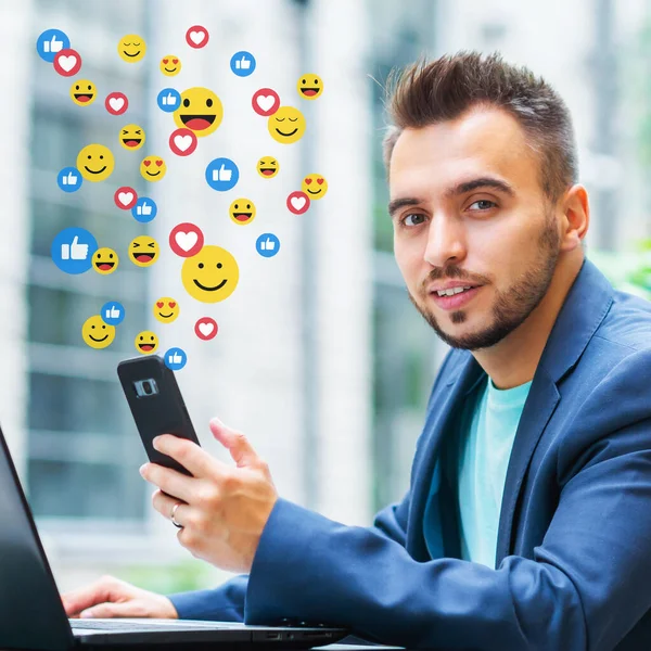 Framgångsrik bloggare tittar på nyhetsflödet från ett socialt nätverk. En man sätter och tar emot likheter och åsikter i form av känsloikoner. Sociala nätverk, internet och online-kommunikation. — Stockfoto