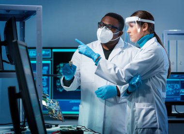 Bir grup mikro elektronik mühendisi modern bir mikroişlemci laboratuvarında tartışıyorlar. Elektronik tasarımcıların işyeri. Yenilikler ve icatlar kavramı.