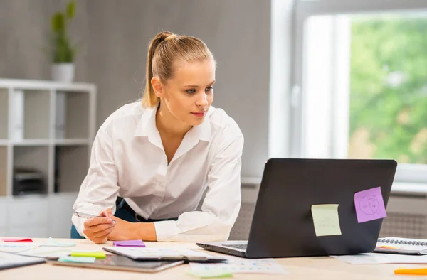 Lugar de trabajo del trabajador independiente o de una estudiante en la oficina del hogar. Mujer joven trabaja usando la computadora y otros dispositivos. Concepto de trabajo remoto. — Foto de Stock