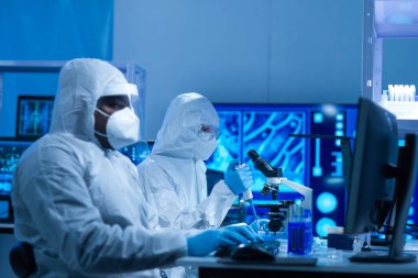 Afrikalı-Amerikalı bilim adamı laboratuvar ekipmanları, mikroskop ve bilgisayar teknolojisi kullanarak bir laboratuarda çalışıyor. Yeni ilaçların ve aşıların icadı. Bilim ve Sağlık kavramı.