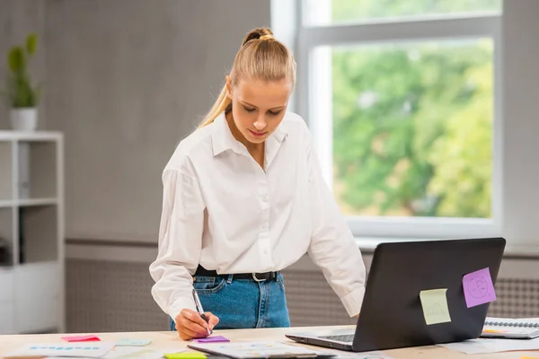 Szabadúszó munkás vagy diáklány munkahelye az otthoni irodában. A fiatal nő számítógéppel és más eszközökkel dolgozik. Távmunka-koncepció. — Stock Fotó