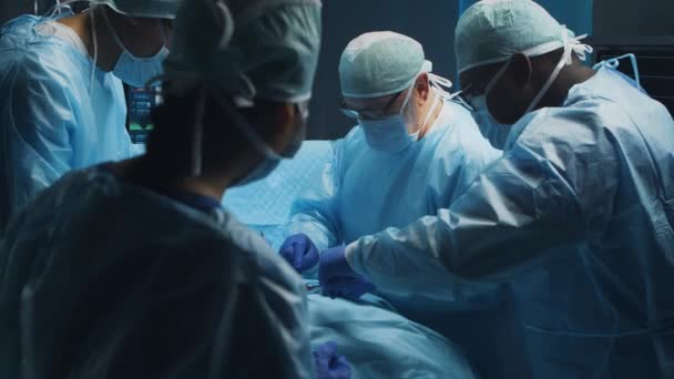 Multiracial team af professionelle medicinske kirurger udfører den kirurgiske operation på et moderne hospital. Lægerne arbejder på at redde patienten. Medicin, sundhed, kardiologi og transplantation. – Stock-video