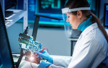 Modern mikro elektronik imalat laboratuvarında çalışan genç bir kadının işyeri. Mühendis, bilgisayar sistemleri ve mikroişlemciler üzerine modern bir bilim laboratuvarında çalışıyor..