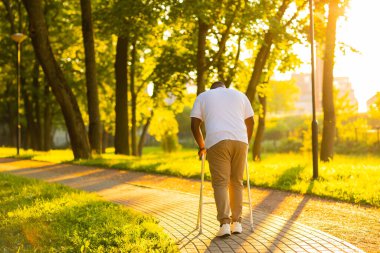 Adam gün batımında Walker 'la dışarıda yürüyor. Rehabilitasyon kavramı.