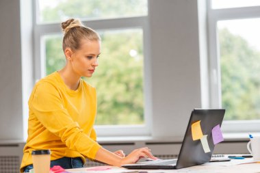 Serbest çalışan bir işçinin ya da öğrenci bir kızın çalıştığı yer. Genç kadın bilgisayar ve diğer cihazları kullanarak çalışıyor. Uzak görev konsepti.