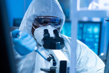 Afrikalı-Amerikalı bilim adamı laboratuvar ekipmanları, mikroskop ve bilgisayar teknolojisi kullanarak bir laboratuarda çalışıyor. Yeni ilaçların ve aşıların icadı. Bilim ve Sağlık kavramı.