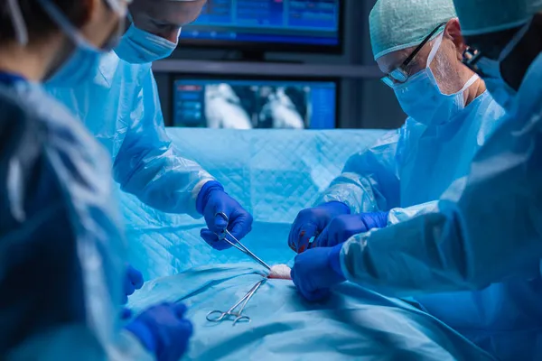 Multiracial team of professional medical surgeons performs the surgical operation in a modern hospital. Doctors are working to save the patient. Medicine, health, cardiology and transplantation. — Stock Photo, Image