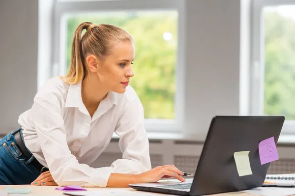 Lugar de trabajo del trabajador independiente o de una estudiante en la oficina del hogar. Mujer joven trabaja usando la computadora y otros dispositivos. Concepto de trabajo remoto. — Foto de Stock