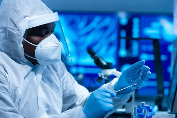 Cientista afro-americano trabalha em um laboratório científico usando equipamentos de laboratório, microscópio e tecnologia da computação. Invenção de novos medicamentos e vacinas. Conceito de Ciência e Saúde. — Fotografia de Stock