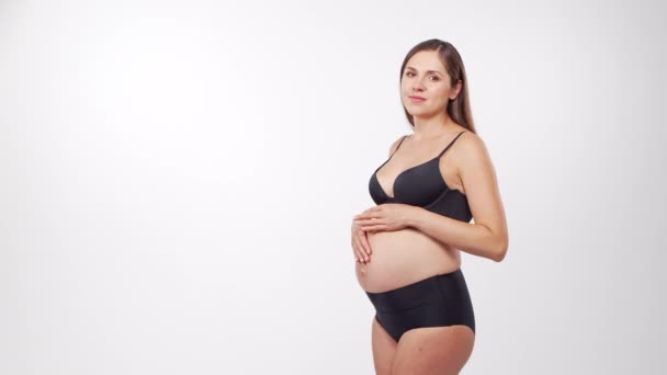 Mujer embarazada joven, feliz y saludable sobre fondo blanco. Vídeo del estudio. Esperanza del bebé, embarazo y concepto de maternidad. — Vídeos de Stock