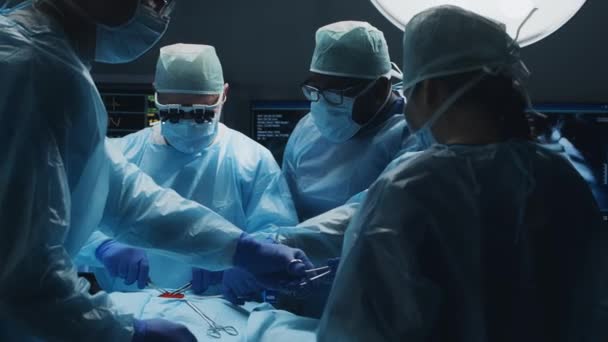 Πολυφυλετική ομάδα επαγγελματιών ιατρών χειρουργών εκτελεί τη χειρουργική επέμβαση σε ένα σύγχρονο νοσοκομείο. Οι γιατροί προσπαθούν να σώσουν τον ασθενή. Ιατρική, υγεία, καρδιολογία και μεταμόσχευση. — Αρχείο Βίντεο
