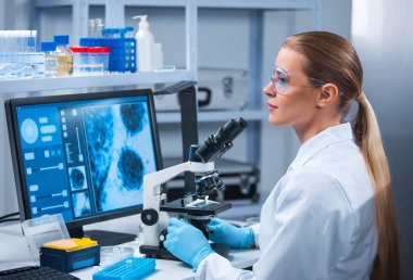 Kadın doktor, bilgisayar teknolojileri ve ekipman kullanarak modern bir bilim laboratuarında çalışıyor. Bilim adamı araştırma yapar ve yeni aşılar geliştirir. Bilim ve sağlık konsepti.