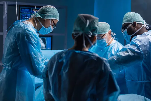 Equipe multirracial de cirurgiões médicos profissionais realiza a operação cirúrgica em um hospital moderno. Os médicos estão a trabalhar para salvar o paciente. Medicina, saúde, cardiologia e transplante. — Fotografia de Stock