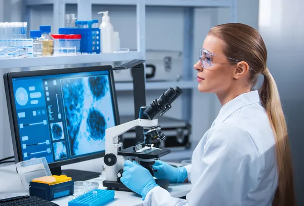 La doctora trabaja en un moderno laboratorio científico usando equipos y tecnologías informáticas. El científico investiga y desarrolla nuevas vacunas. Concepto de ciencia y salud. —  Fotos de Stock