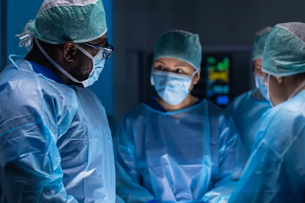 El equipo multirracial de cirujanos médicos profesionales realiza la operación quirúrgica en un hospital moderno. Los médicos están trabajando para salvar al paciente. Medicina, salud, cardiología y trasplante. —  Fotos de Stock