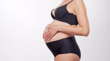 Genç, mutlu ve sağlıklı hamile bir kadın beyaz arka planda. Stüdyo videosu. Bebek beklentisi, hamilelik ve annelik kavramı.