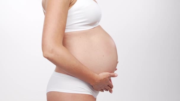 Mujer embarazada joven, feliz y saludable sobre fondo blanco. Vídeo del estudio. Esperanza del bebé, embarazo y concepto de maternidad. — Vídeo de stock