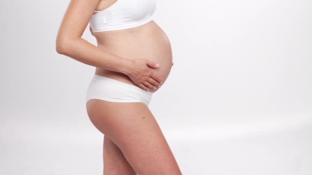 Молода, щаслива і здорова вагітна жінка на білому тлі. Студійне відео. Дитячі очікування, вагітність та концепція материнства . — стокове відео