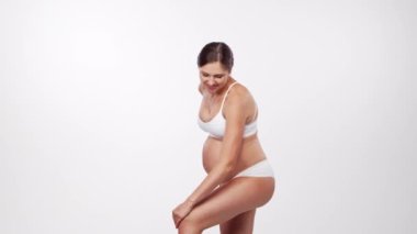 Genç, mutlu ve sağlıklı hamile bir kadın beyaz arka planda. Stüdyo videosu. Bebek beklentisi, hamilelik ve annelik kavramı.