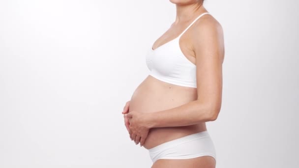 Fiatal, boldog és egészséges terhes nő fehér háttérrel. Stúdió videó. Baba elvárás, terhesség és anyaság koncepció. — Stock videók